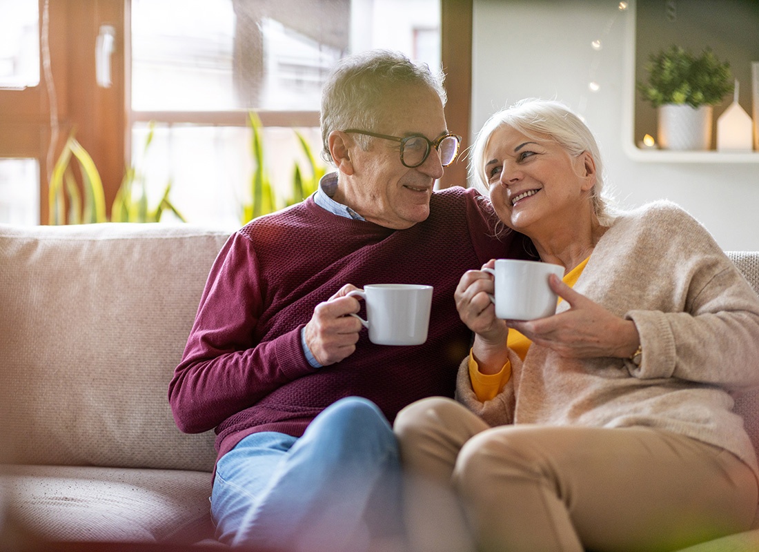 Medicare - Portrait of a Happy Senior Couple Enjoying a Cup of Coffee in the Morning While Sitting Together on the Sofa at Home